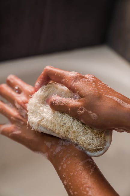Hands scrubbing with a loofah in a bath setting, focusing on personal hygiene.